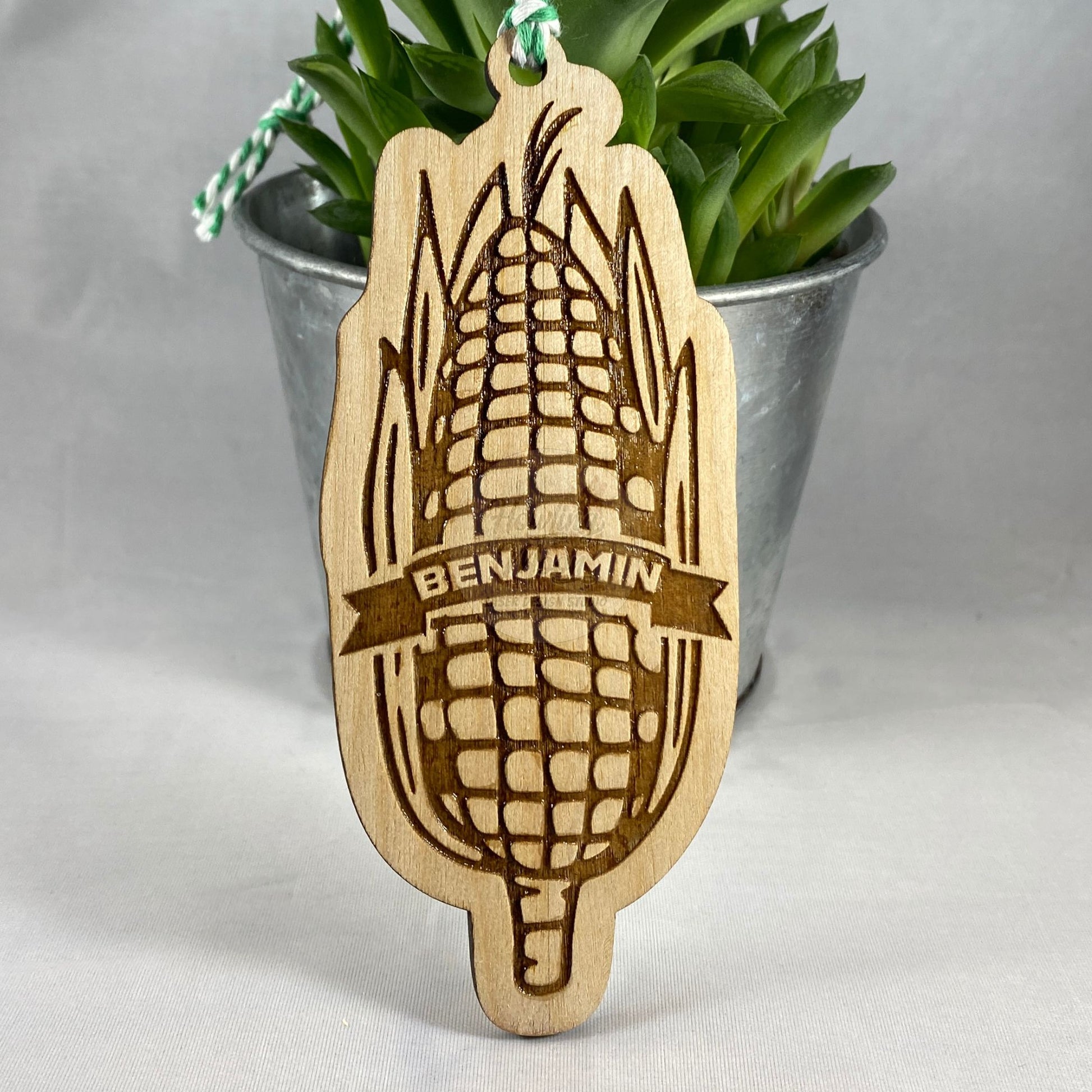 Close up of Personalized Sweet Corn Ornament from Howling Moon Laser Design features hand drawn ear of corn and twine ribbon for hanging