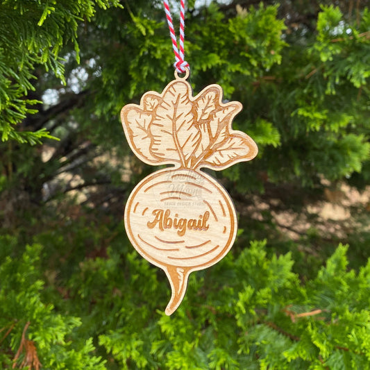 Personalized garden beet ornament with red & white twine ribbon hanging from a coniferous tree - made by Howling Moon Laser Design in Virginia USA